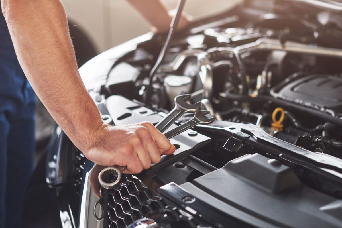 Picture showing muscular car service worker repairing vehicle.